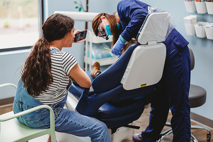 Smiling mom and dental hygienist working with a child